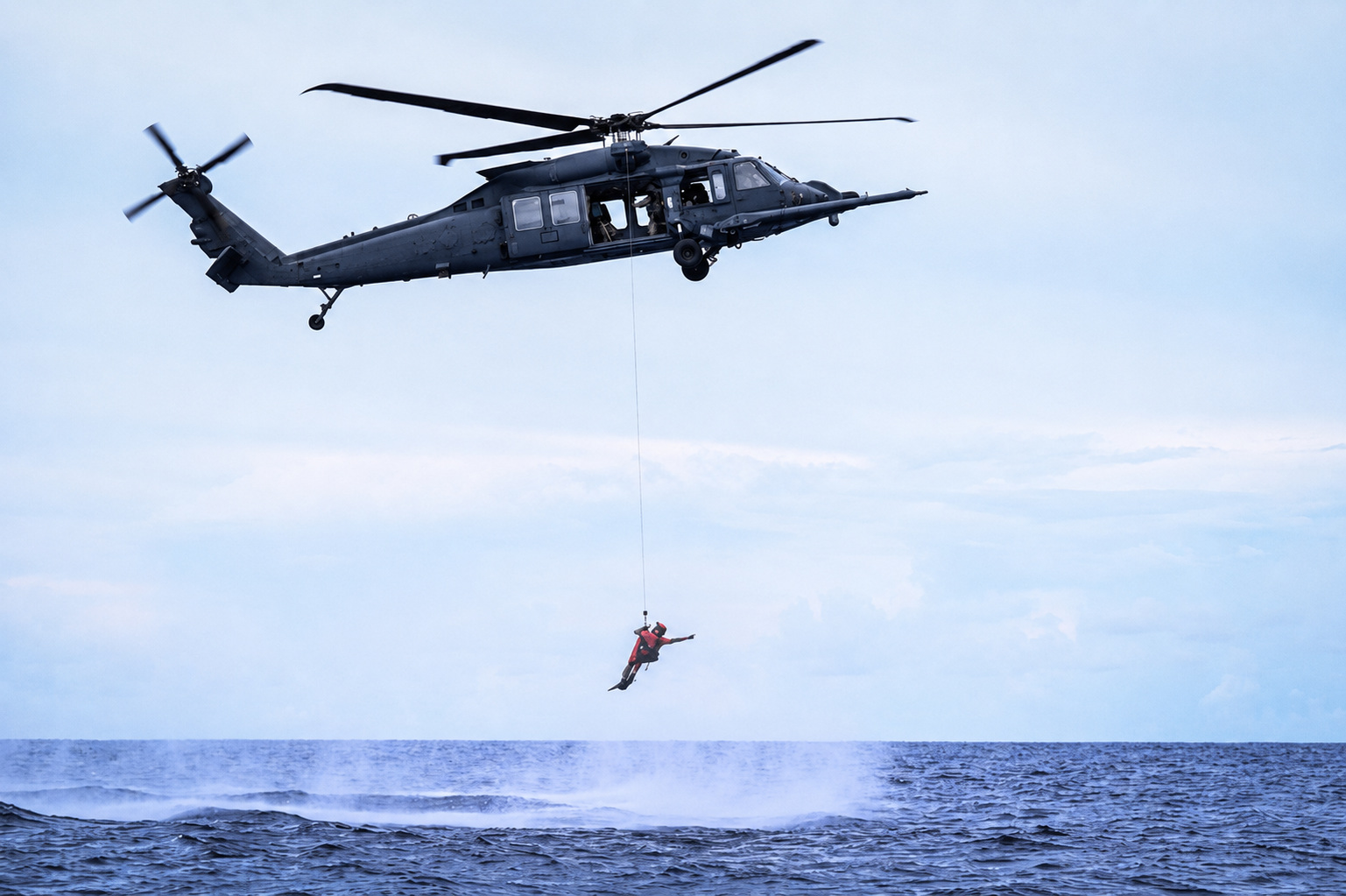 U.S. Air Force HH-60W Jolly Green II helicopter conducting a simulated ocean rescue hoist